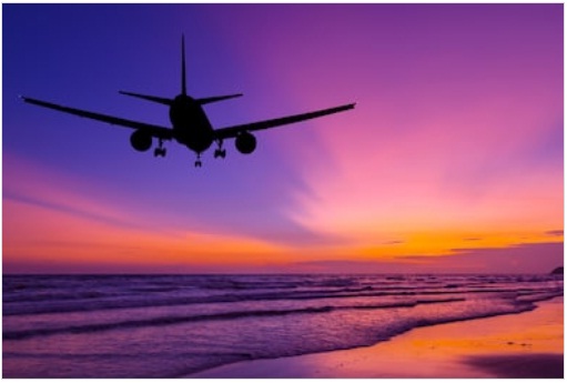 Airplane flying above the sea at sunset