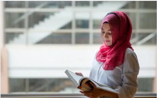 باحجاب مسلمان طالبہ کتاب کا مطالعہ کرتے ہوئے