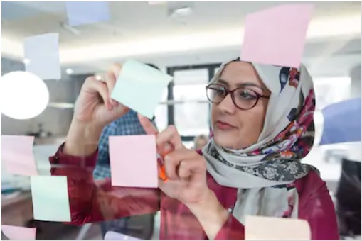باحجاب لڑکی دفتر میں سٹکی نوٹس لگاتے ہوئے