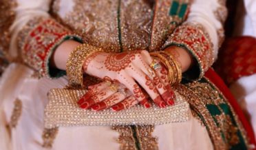 دلہن کے مہندی سے سجے ہوئے ہاتھوں ، روایتی جیولری پہنے شادی کے دن سٹیج پر بیٹھے ہوئے
