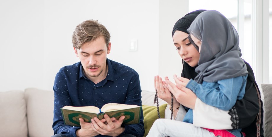 مسلمان شوہر قرآن پڑھتے ہوئے ، بیوی اور بیٹی پاس بیٹھی ہیں