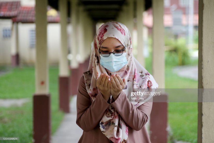 مسلمان خاتون ماسک پہنے دعا مانگ رہی ہے