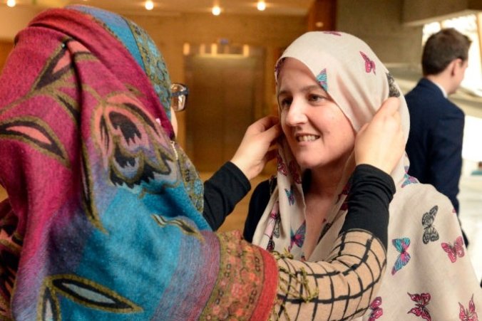 ایک مسلمان خاتون دوسری خاتون کو سکھا رہی ہے کہ حجاب کیسے پہنتے ہیں