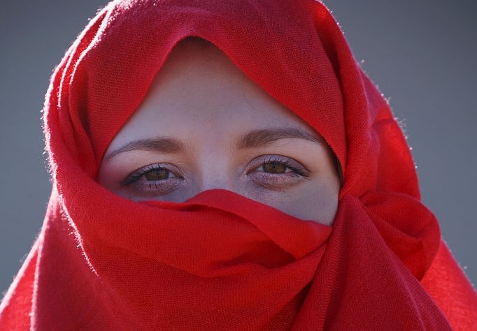 مسلمان خاتون سرخ چادر سے حجاب کئے ہوئے