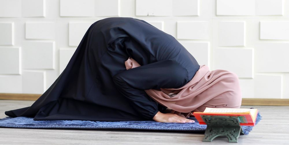 نوجوان مسلمان باحجاب خاتون نماز میں سجدہ کرتے ہوئے