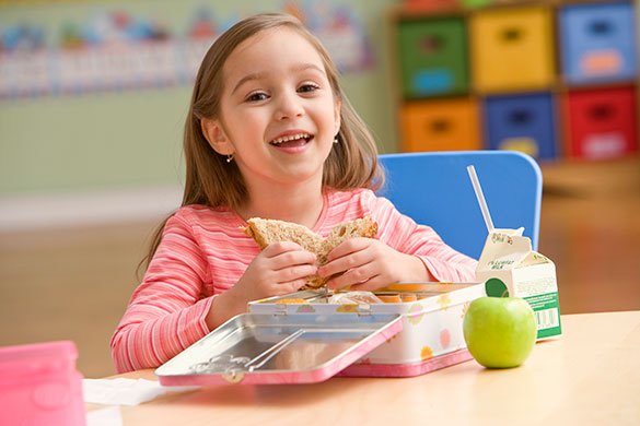 لڑکی سکول میں سینڈوچ ، سیب اور دودھ سے لنچ کر رہی ہے