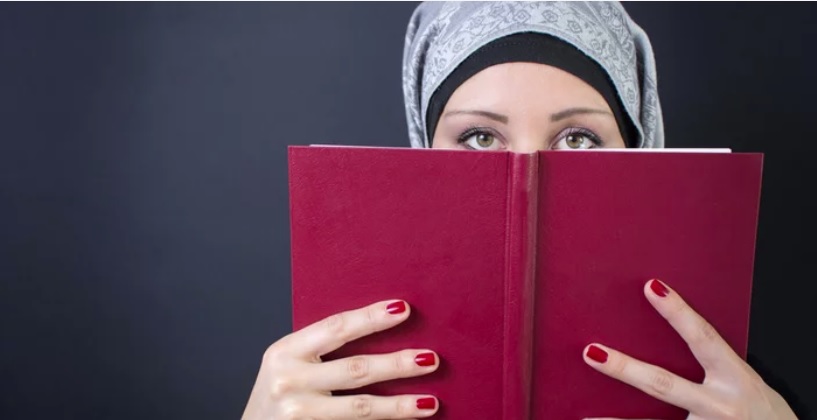 خوبصورت باحجاب مسلمان خاتون کتاب چہرے پر رکھ کر دیکھ رہی ہے